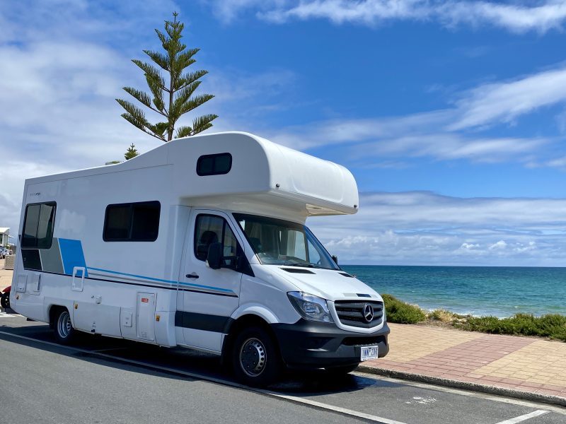 Large motorhome campervan parked next to a beach with view of the ocean